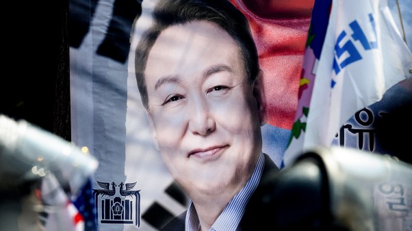 Riot police stand guard near a banner with a photo of South Korea president Yoon Suk Yeol.