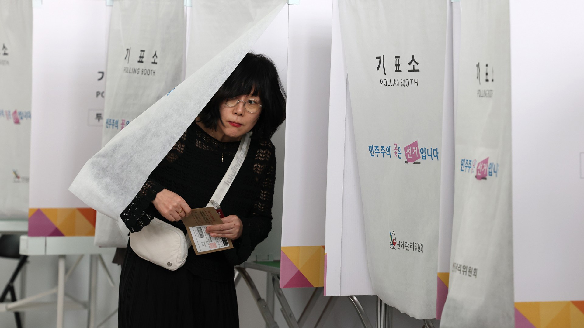 A woman comes out of a booth to cast her early vote in a polling station for the presidential election in South Korea.